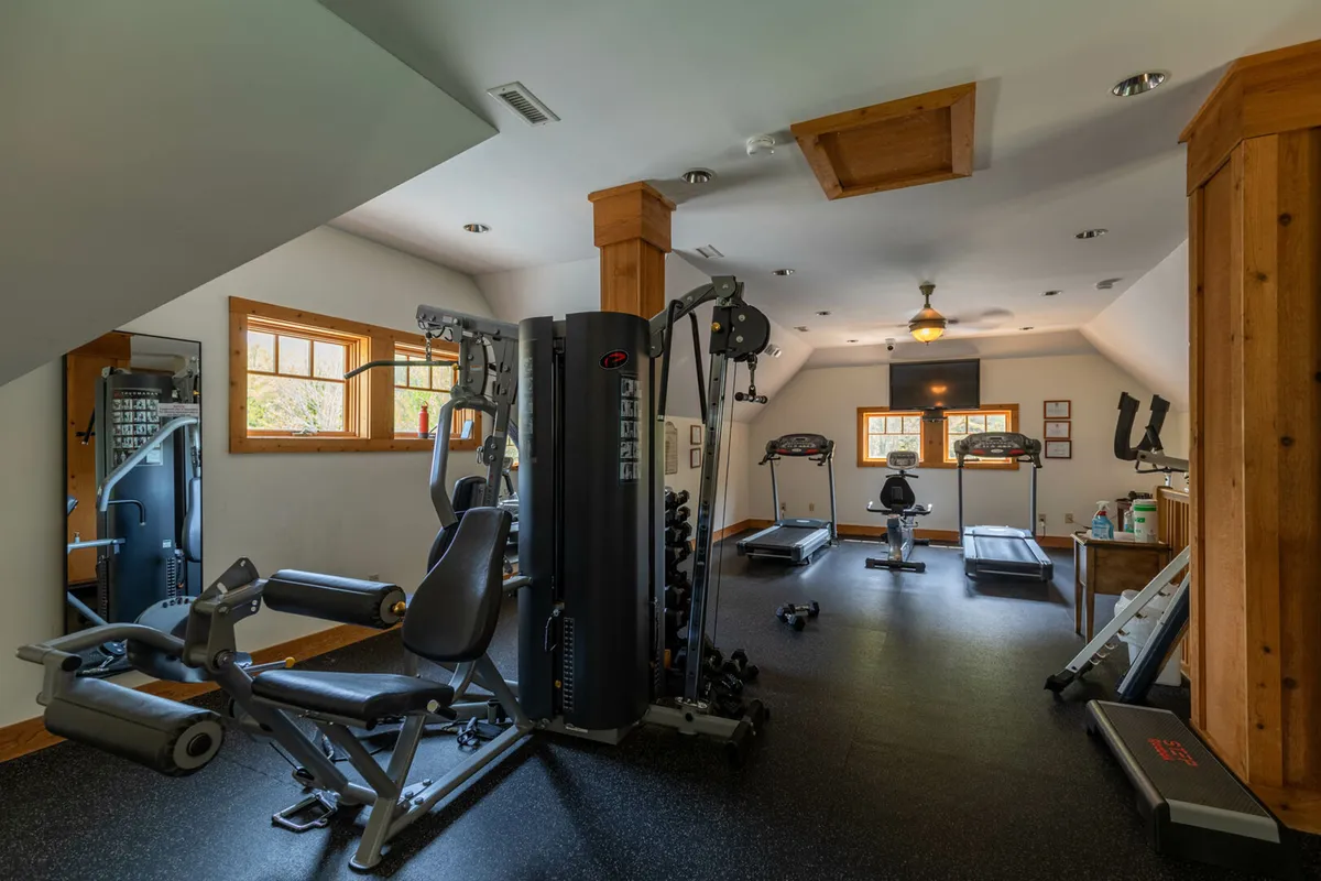 A bright, spacious fitness center filled with multi-gym equipment, treadmills, and large windows letting in natural light, offering views of the outdoors and an energizing atmosphere for workouts or group fitness activities.
