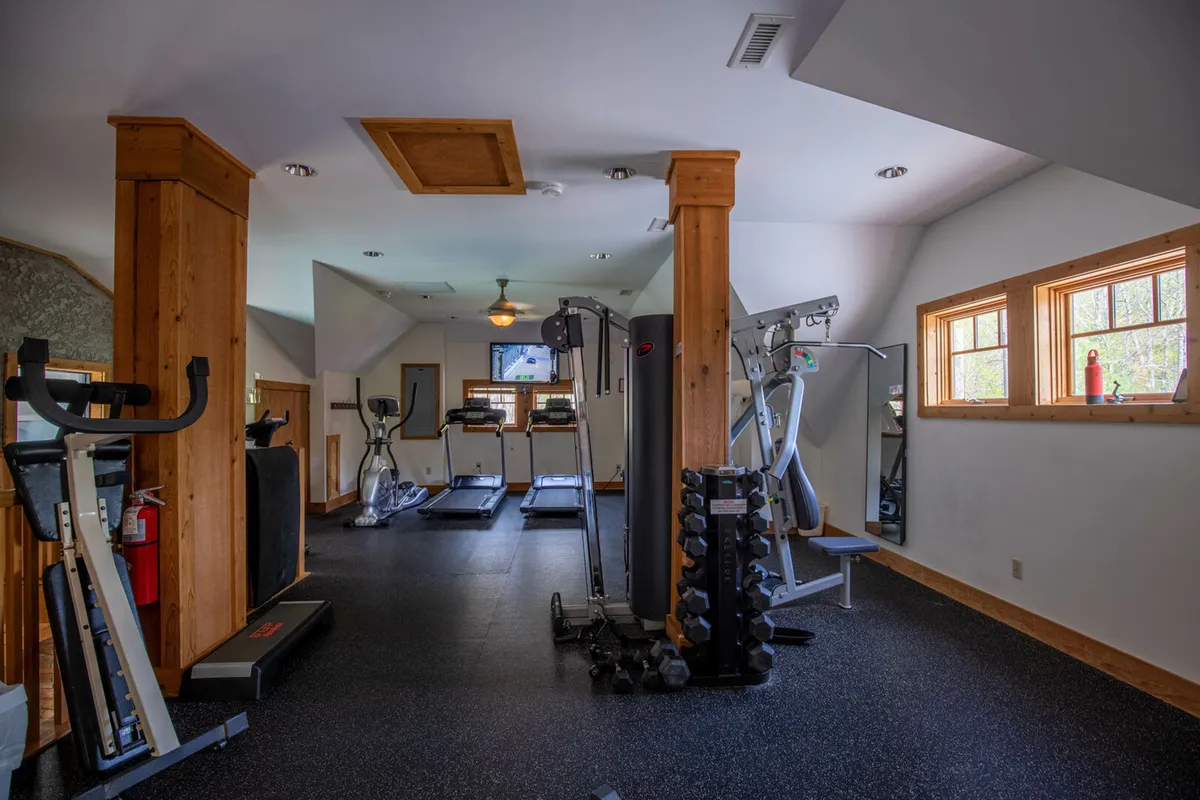 An interior shot of a well-equipped fitness center featuring treadmills, weightlifting equipment, and large windows that let in abundant natural light. The space feels active and energetic, designed for both solo and group fitness pursuits.