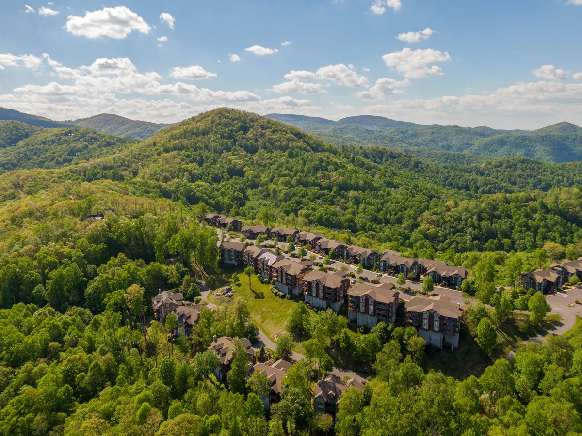 This image showcases lush green hills and modern apartment buildings set against spacious lawns, conveying the natural beauty and outdoor spaces available within the Bear Crossing at Echota community. The scene is tranquil yet inviting, perfect for highlighting the resort’s proximity to outdoor adventure and its access to scenic surroundings.