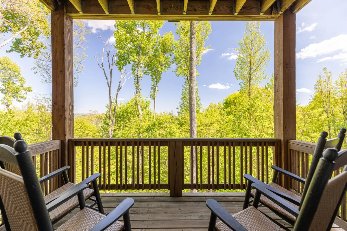 A serene deck space with rocking chairs overlooking lush greenery and the open sky. The setting radiates peace and togetherness—a place to gather, share stories, and enjoy fresh mountain air as a family.